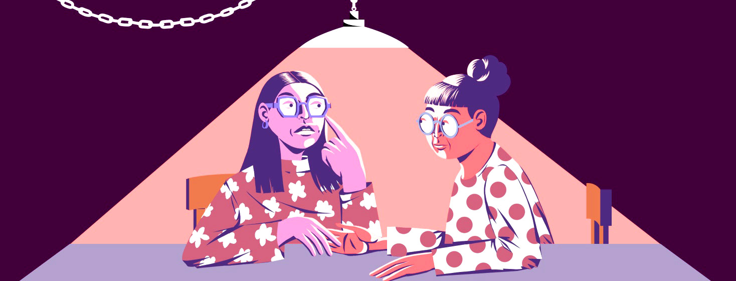 two women chat under a light, one is listening to the other