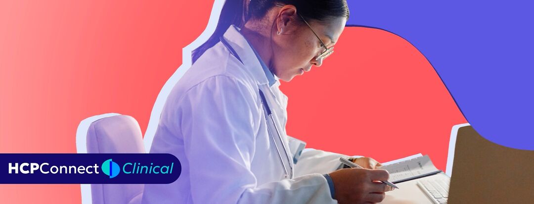 A female doctor sits at her desk and reviews notes.