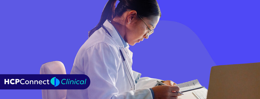 A female doctor sits at her desk and reviews notes.